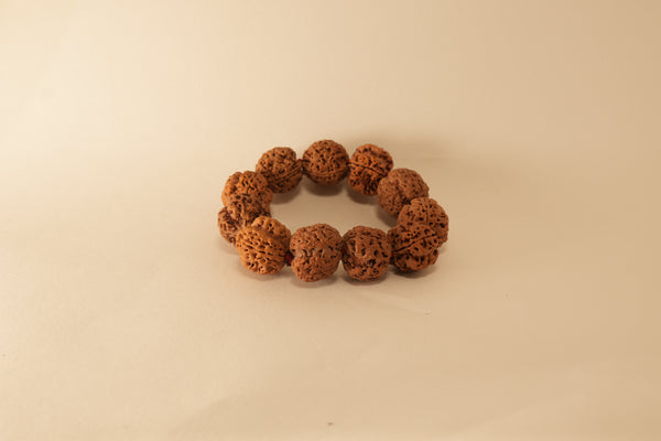 Brown 5 mukhi rudraksha beads bracelet with textured natural seed surface on a beige background